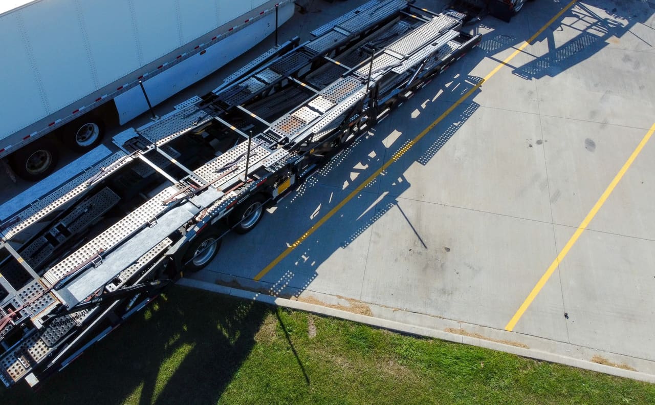 A car carrier's decks and loading ramps seen from directly above, grating and tie-down rails running the length of the trailer.