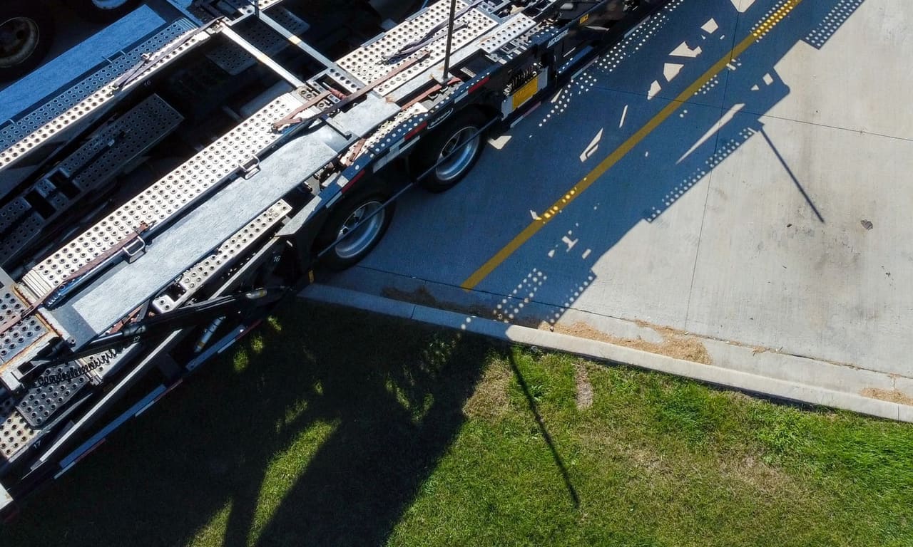 The ramps and upper deck of a car carrier from above, hydraulic rams and walkway grating in close detail.