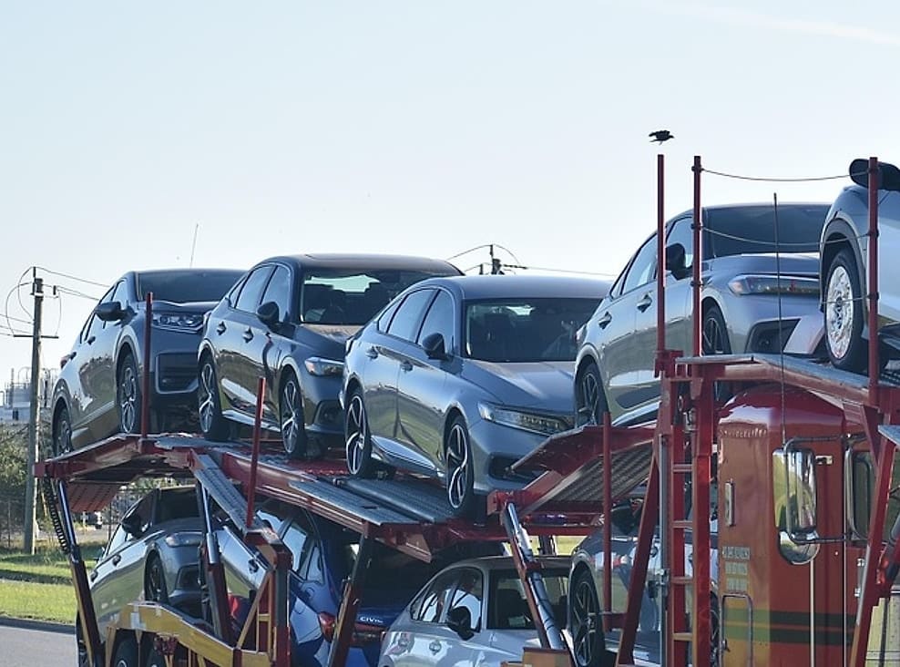 The upper and lower decks of a loaded car carrier, saloons and SUVs racked nose to tail between the uprights.